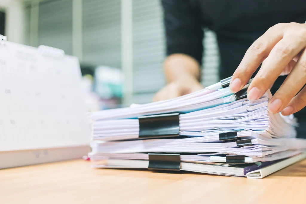 hand of businessman for searching information in stacks of paper